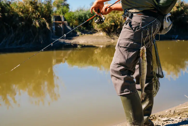 Fish hanging on Fisherman's belt with fishing rod