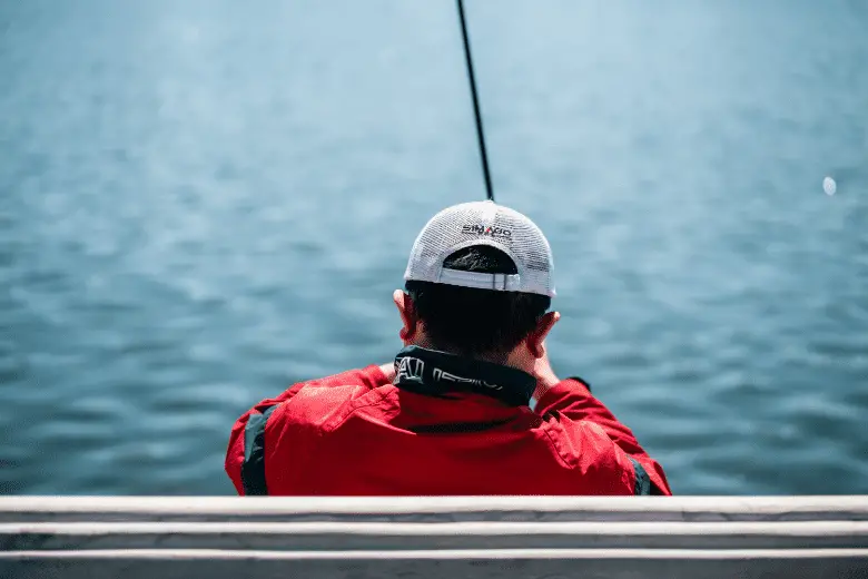 A person facing body of water and fishing