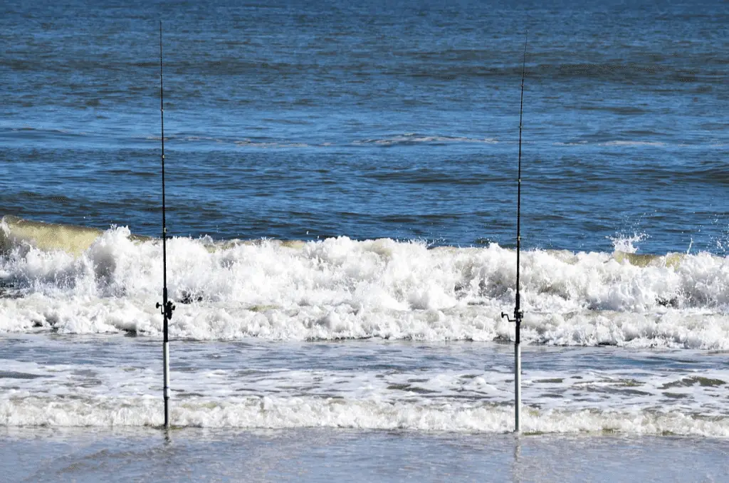 surf fishing poles standing up in the beach