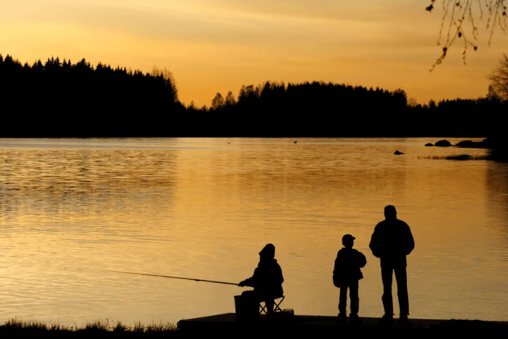 Three people fishing at sunset