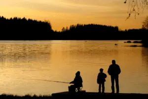 Three people fishing at sunset