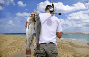 Fisherman carrying fish at a sandy beach