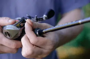Close-up of a male hand with a baitcasting reel.
