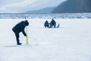 Man fishing through a hole in the frozen lake