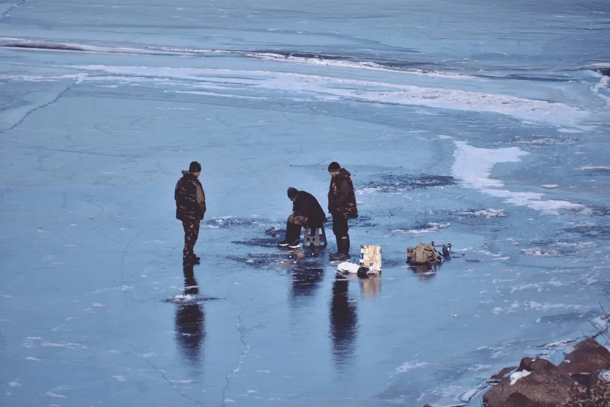 top view of three men ice fishing on a frozen lake