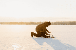 Man looking inside a hole for ice fishing