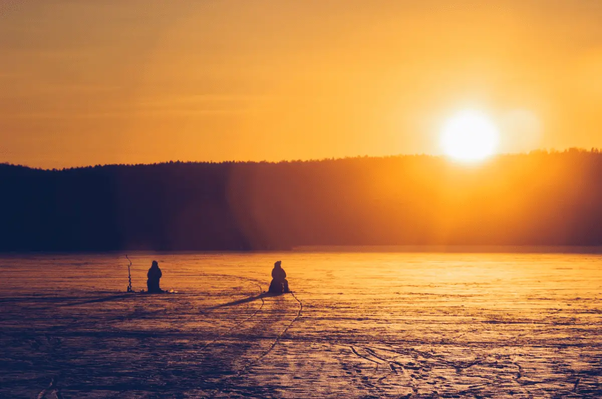 two men ice fishing during beautiful sunset