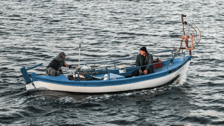 two people on a fishing boat in the middle of the water