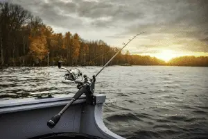 fishing road attached on a boat in the middle of a lake