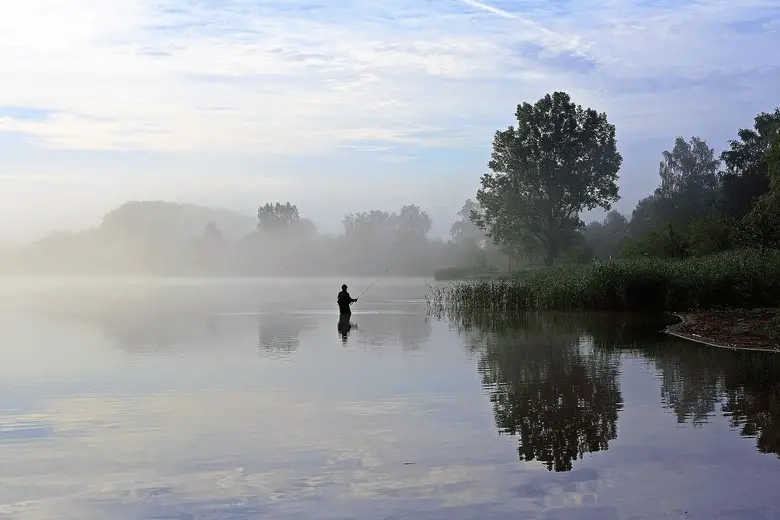 man fishing in a foggy lake