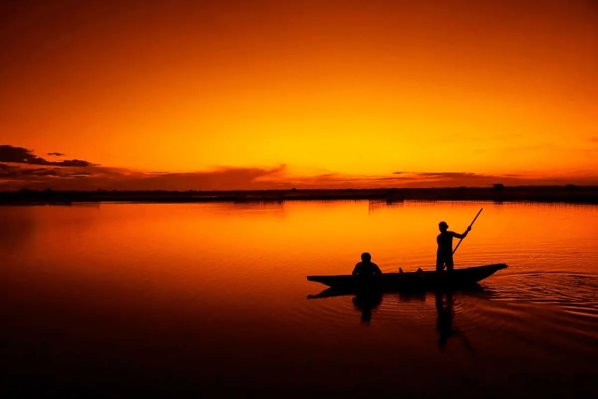 two anglers fishing from a boat at sunset