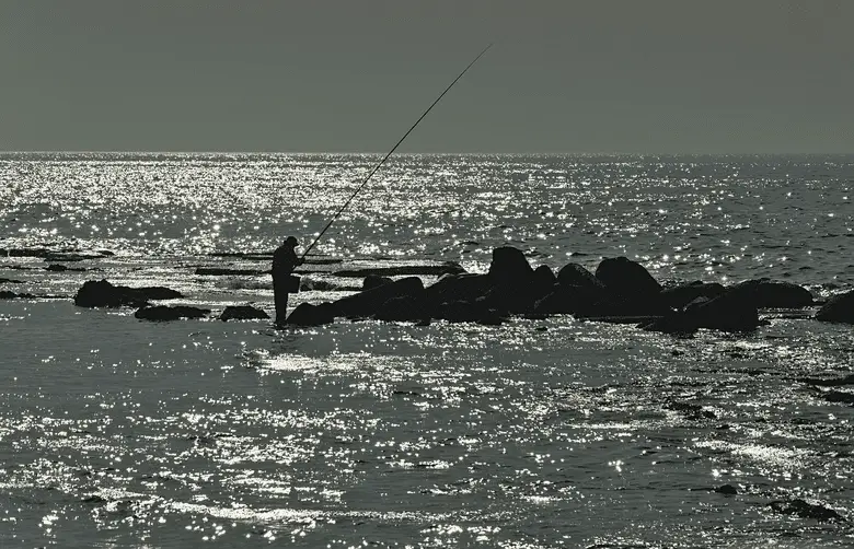 silhouette of an angler fishing in the distance