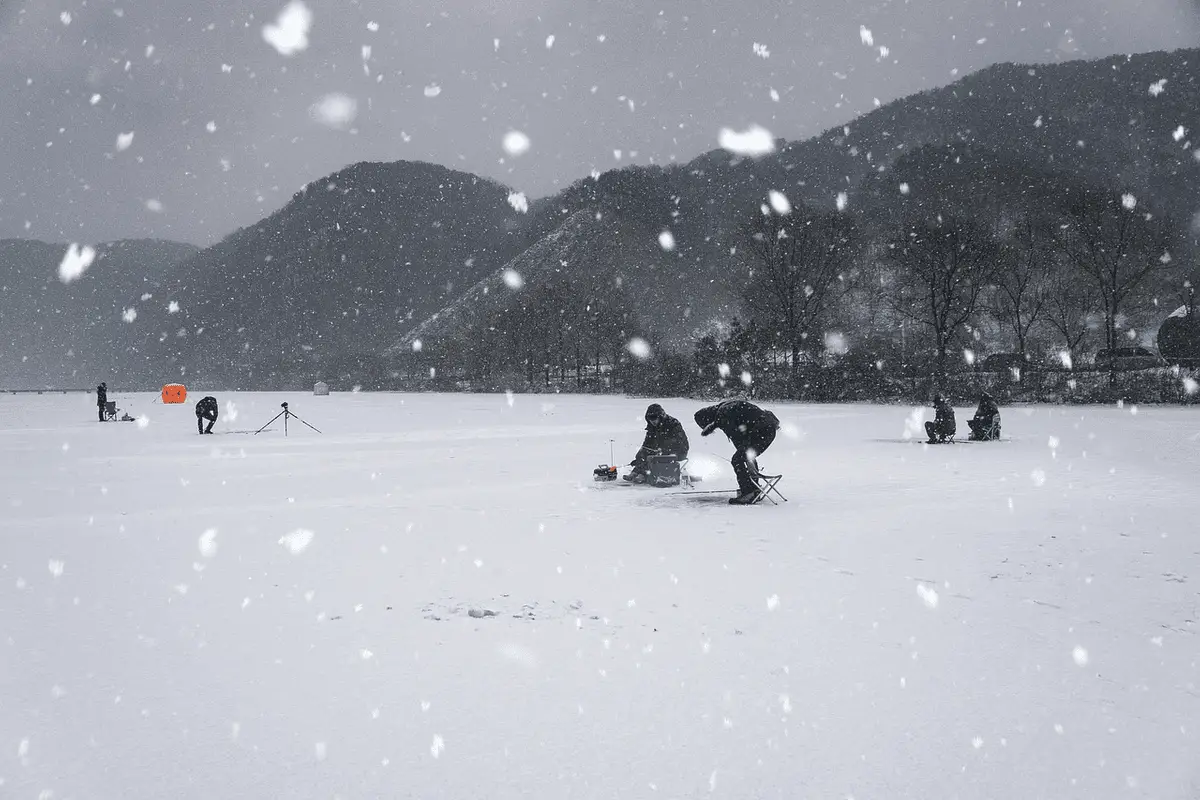 group of anglers ice fishing during a snow storm