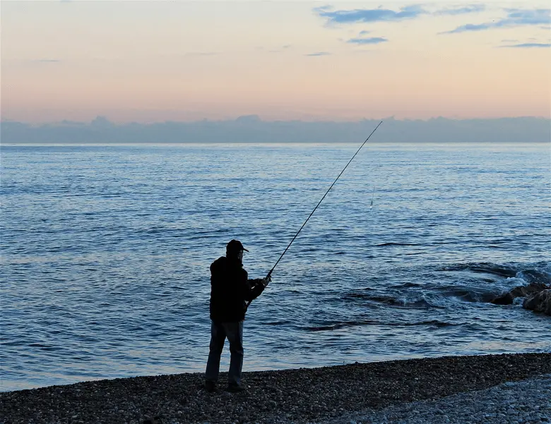angler fishing at sunset on the sea shore