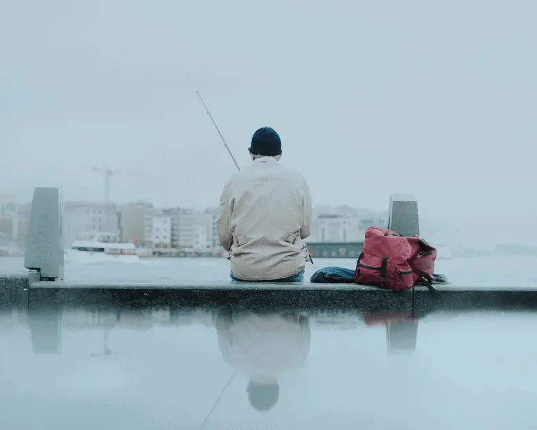 angler sitting on the dock fishing in the rain