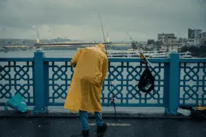 angler in yellow rainjacket fishing from the bridge