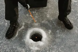 A man standing on the ice with a fishing pole.