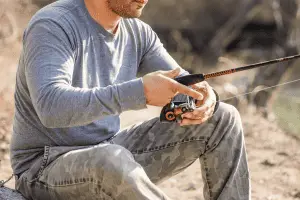 A man sitting on a rock with a fishing rod.