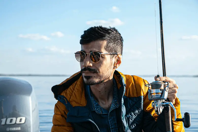 A man holding a fishing rod on a boat.
